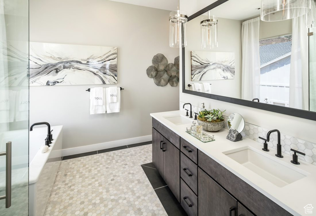 Bathroom featuring tile floors, a bathtub, double sink, and vanity with extensive cabinet space
