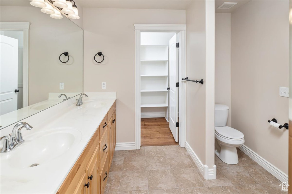 Bathroom with double vanity, tile floors, and toilet