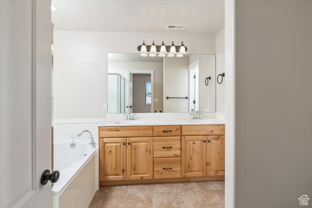 Bathroom featuring tile floors, dual bowl vanity, and a bath