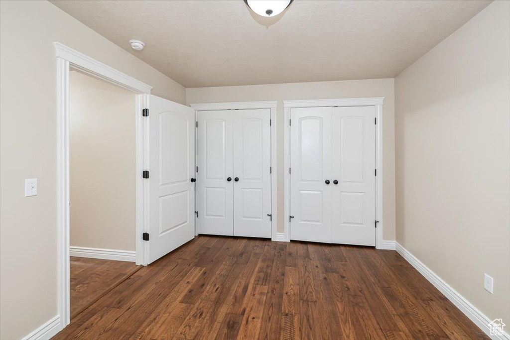 Unfurnished bedroom with dark wood-type flooring and multiple closets