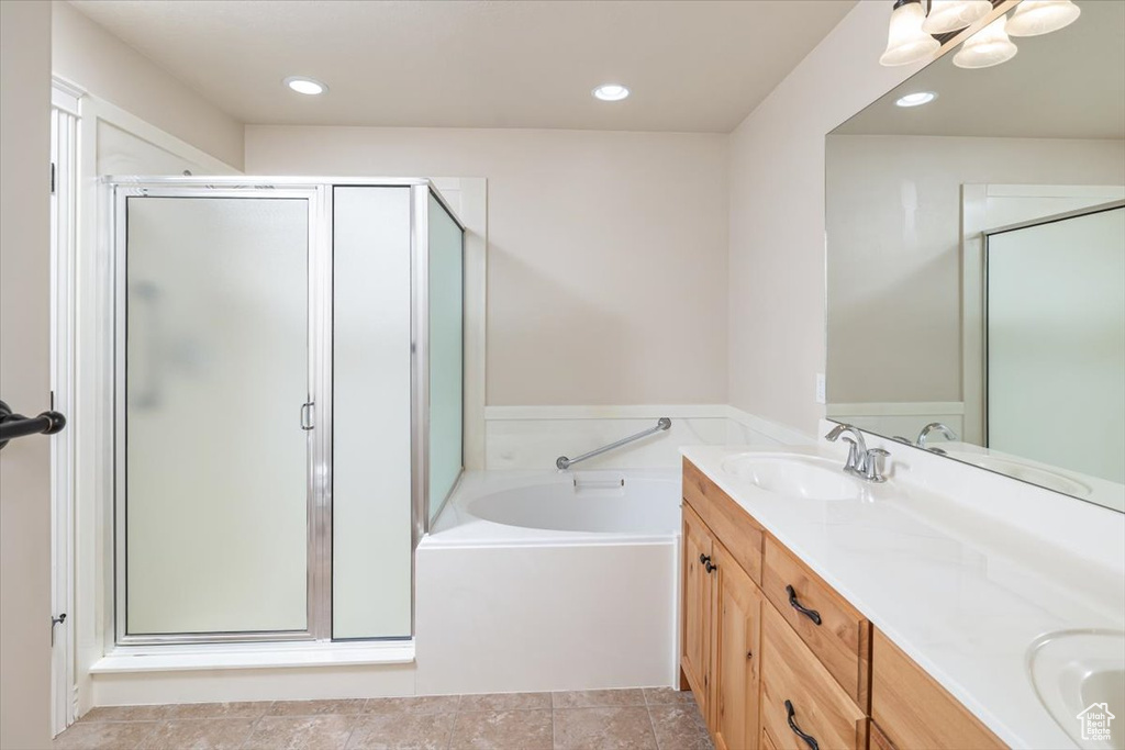 Bathroom featuring double sink vanity, shower with separate bathtub, and tile flooring