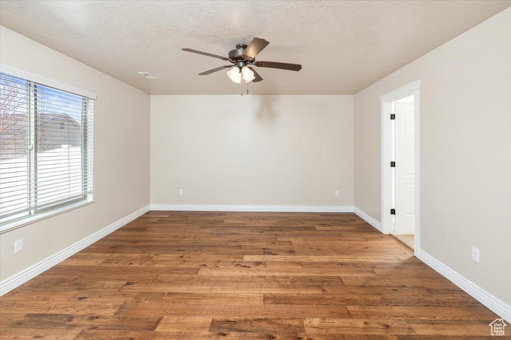 Spare room with ceiling fan, dark wood-type flooring, and a healthy amount of sunlight