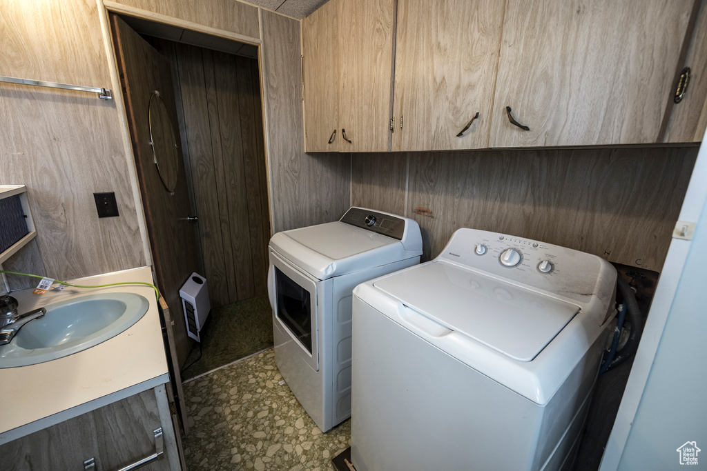 Washroom featuring sink, wooden walls, tile flooring, and washer and dryer