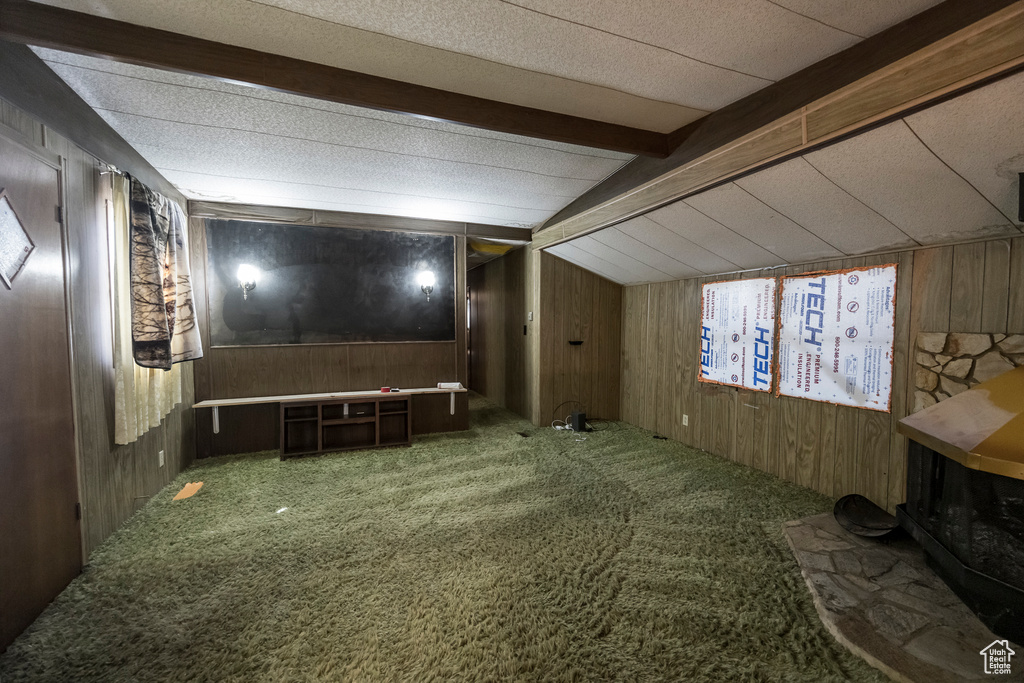 Carpeted cinema featuring beamed ceiling and wood walls