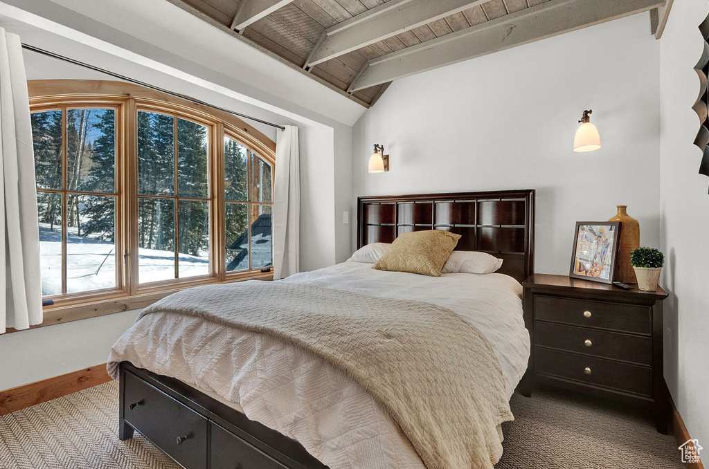 Carpeted bedroom with vaulted ceiling with beams and wood ceiling