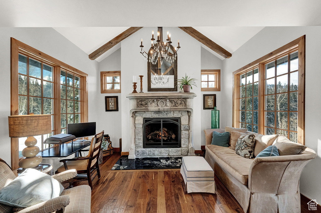 Living room featuring dark wood-type flooring, a chandelier, vaulted ceiling with beams, and a stone fireplace