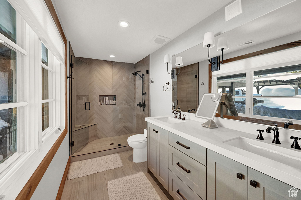 Bathroom with toilet, dual bowl vanity, and walk in shower