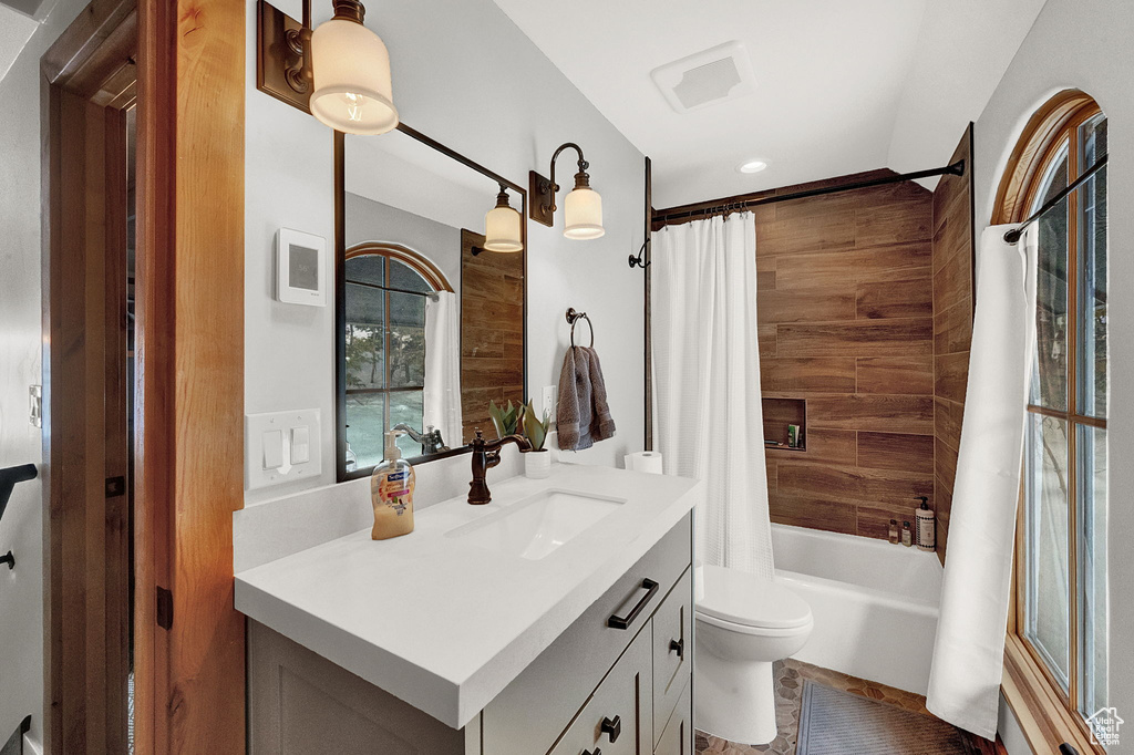 Full bathroom with large vanity, toilet, shower / bath combo, and tile flooring
