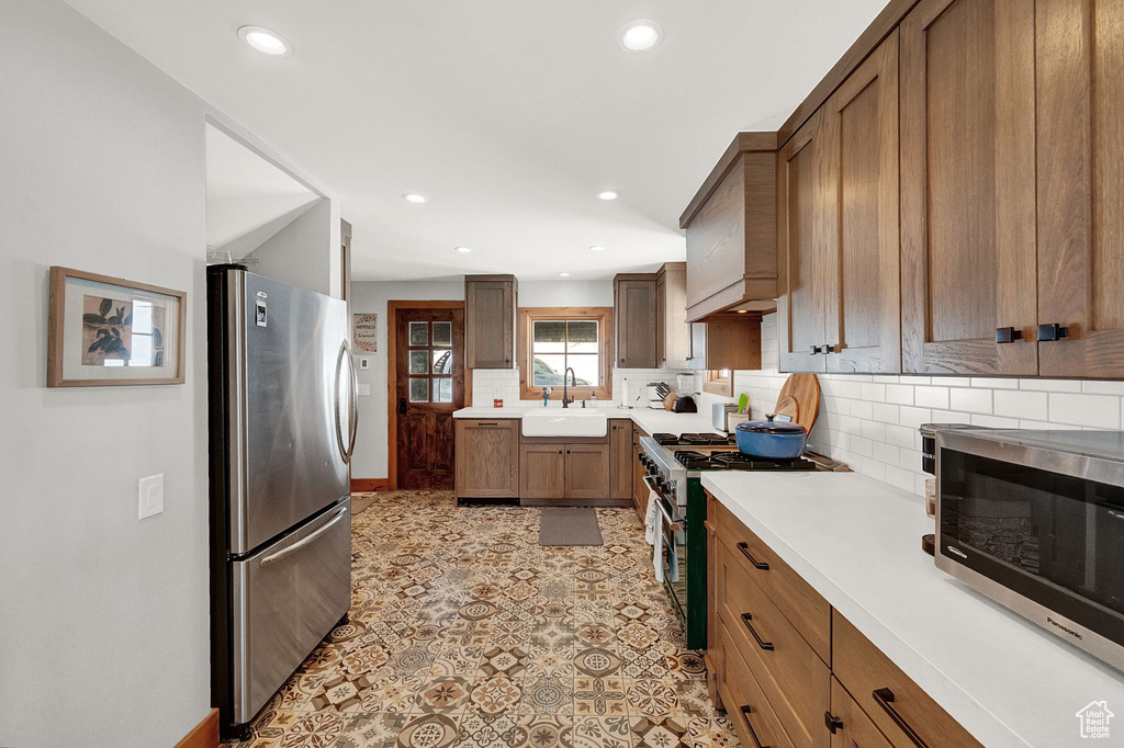 Kitchen with sink, stainless steel appliances, light tile flooring, and backsplash