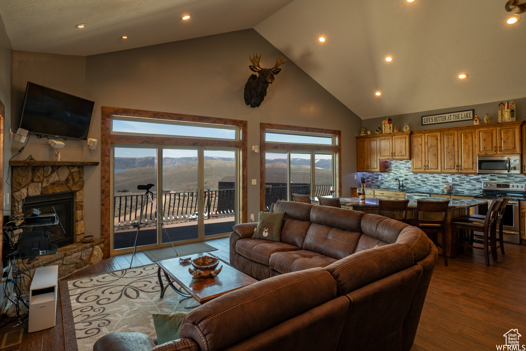 Living room with a fireplace, light hardwood / wood-style flooring, high vaulted ceiling, and a mountain view