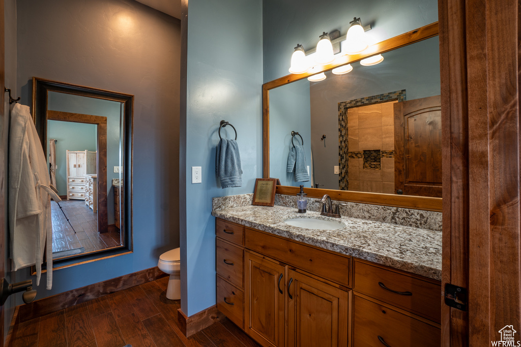 Bathroom with hardwood / wood-style flooring, oversized vanity, and toilet