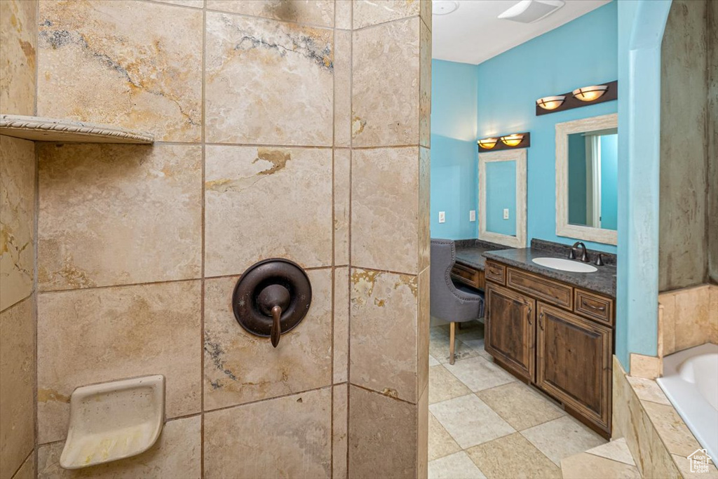 Bathroom with tiled bath, vanity, tile walls, and tile floors