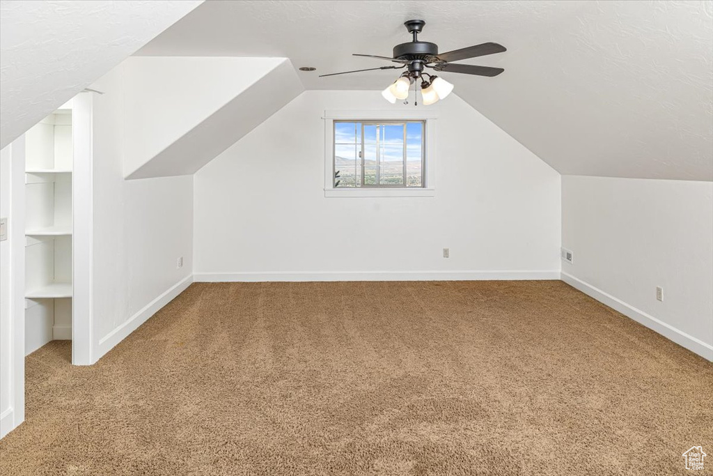 Additional living space featuring ceiling fan, lofted ceiling, and carpet flooring