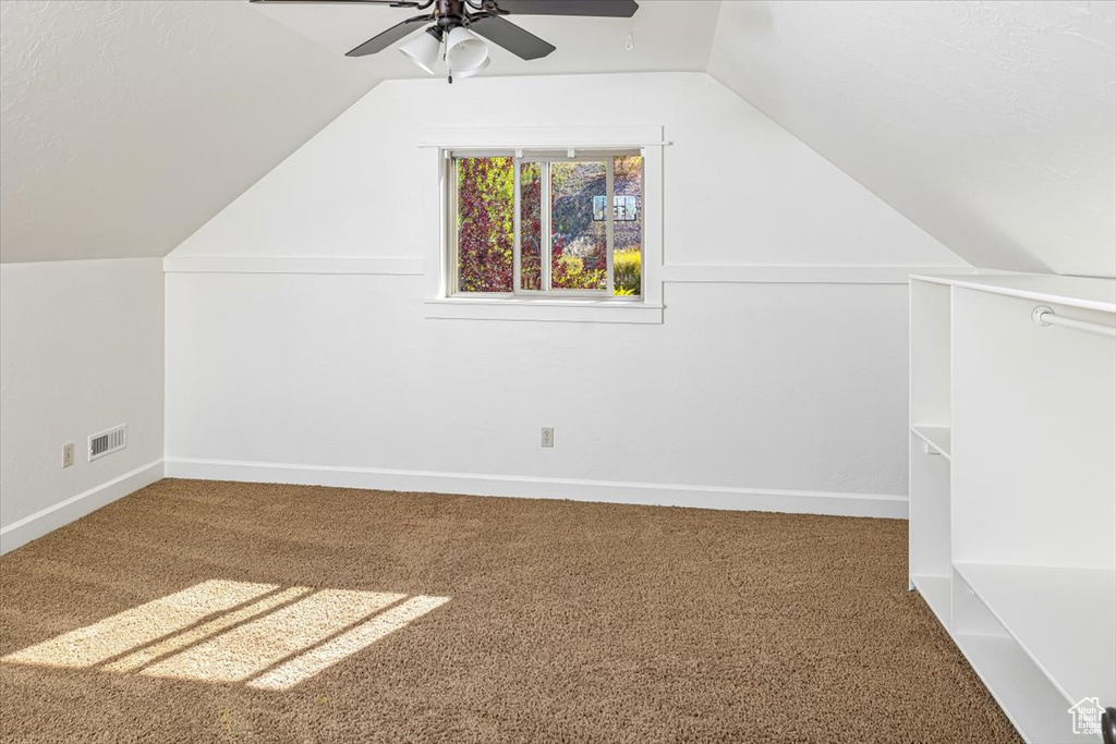 Additional living space featuring ceiling fan, vaulted ceiling, and dark carpet