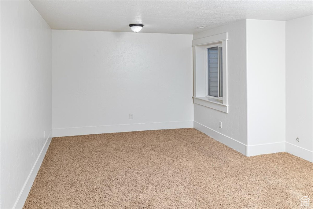 Empty room featuring a textured ceiling and carpet floors
