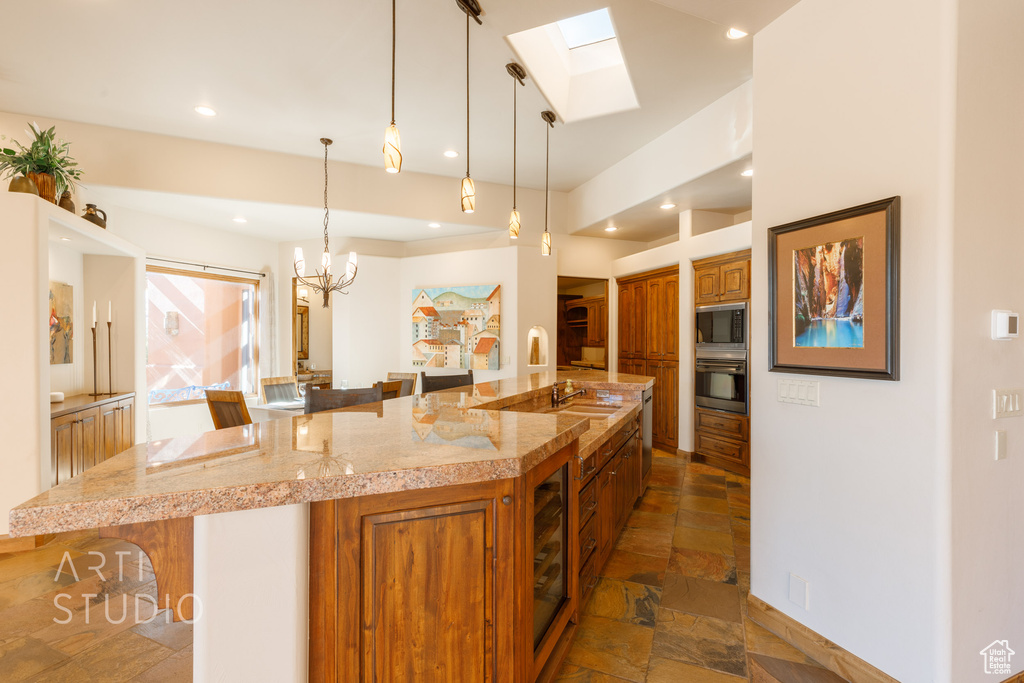 Kitchen with a notable chandelier, a breakfast bar area, a skylight, oven, and built in microwave