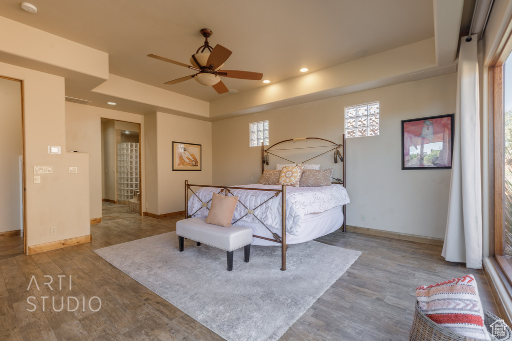Bedroom featuring light hardwood / wood-style floors, a tray ceiling, and ceiling fan