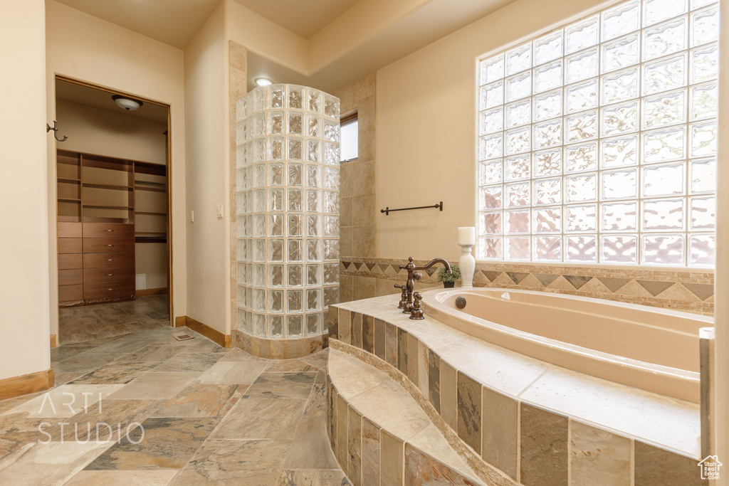 Bathroom featuring a relaxing tiled bath and tile flooring