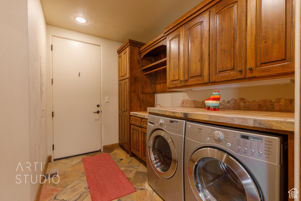 Laundry area with cabinets, light tile flooring, and separate washer and dryer