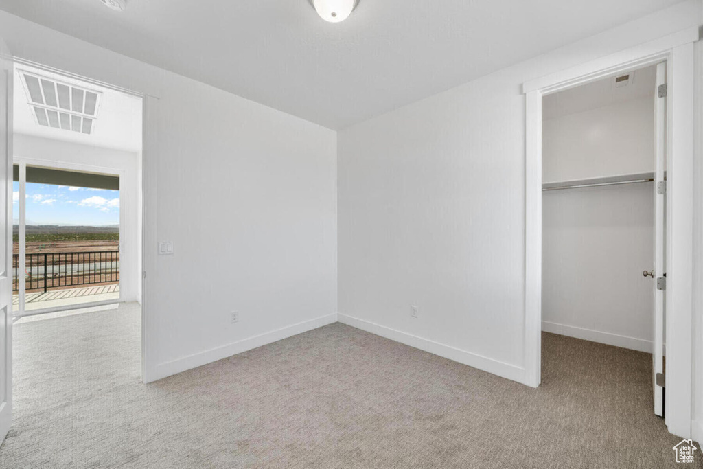 Unfurnished bedroom with a closet, a spacious closet, and light carpet