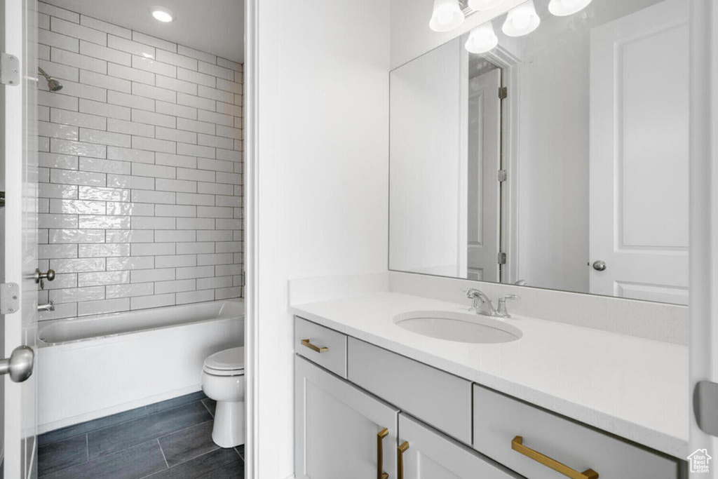 Full bathroom featuring toilet, tiled shower / bath, oversized vanity, and tile flooring
