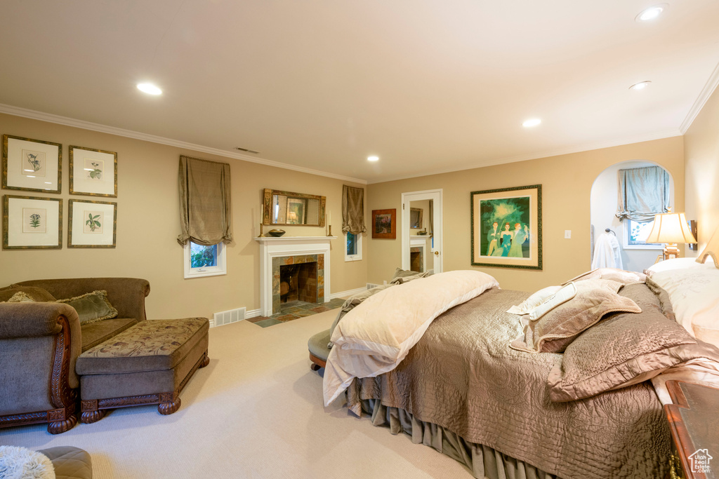Carpeted bedroom with a fireplace and ornamental molding