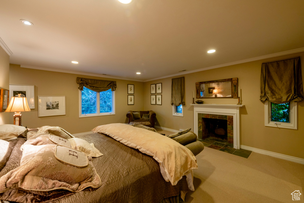 Bedroom featuring dark carpet, crown molding, and a tile fireplace