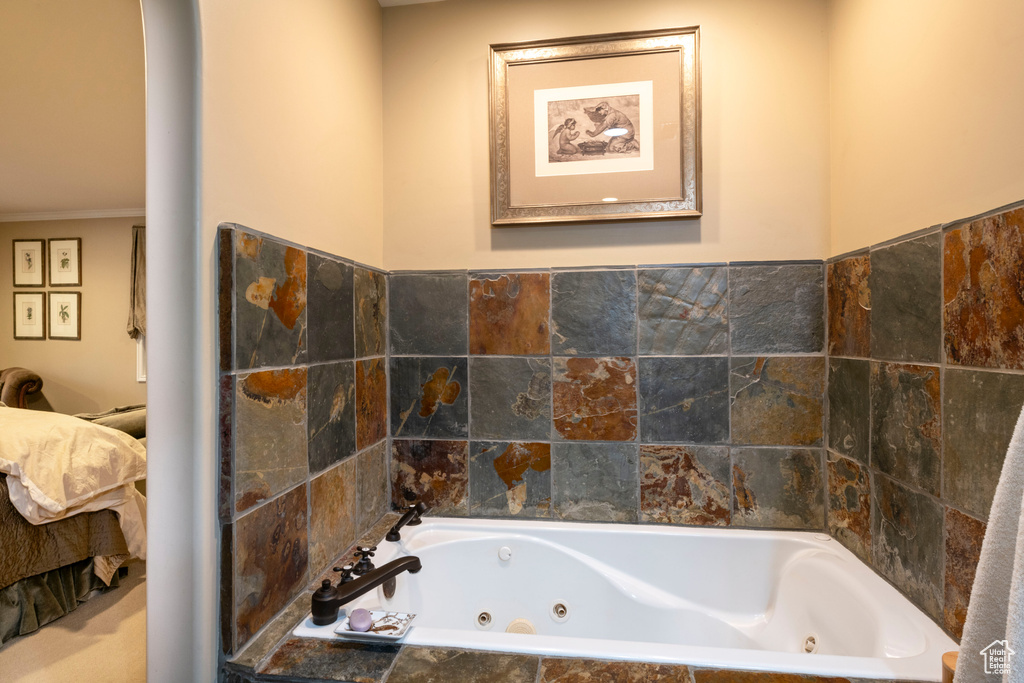 Bathroom with crown molding and tiled bath