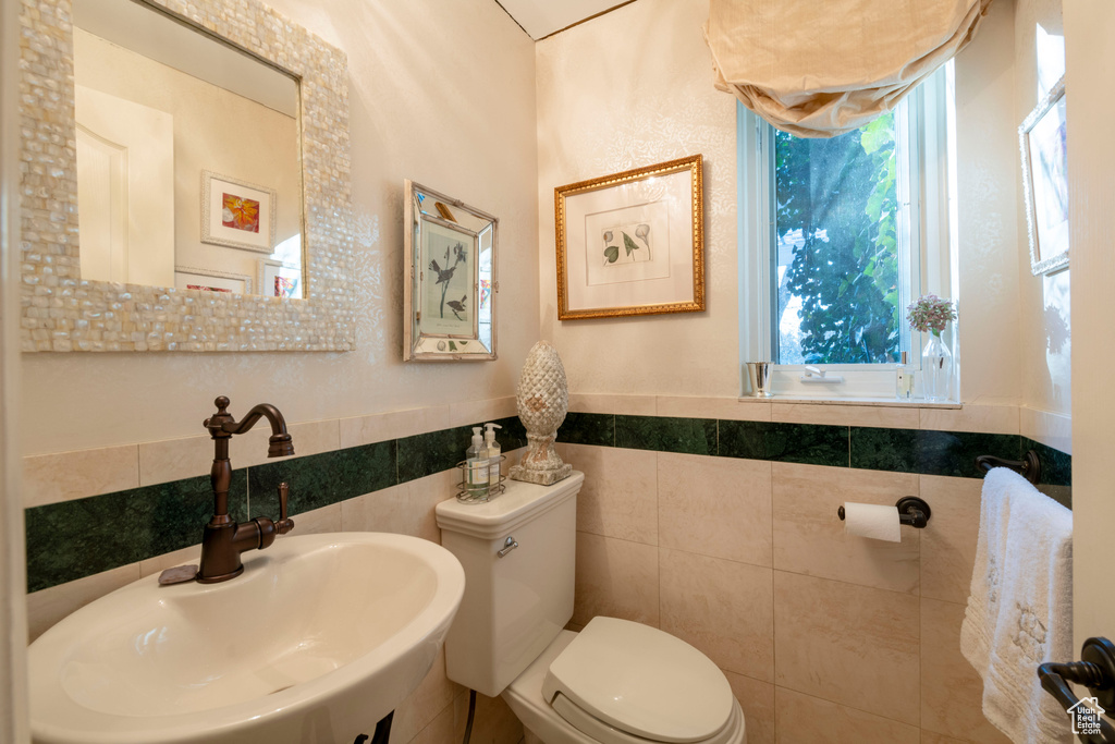 Bathroom with toilet, tile walls, and a wealth of natural light