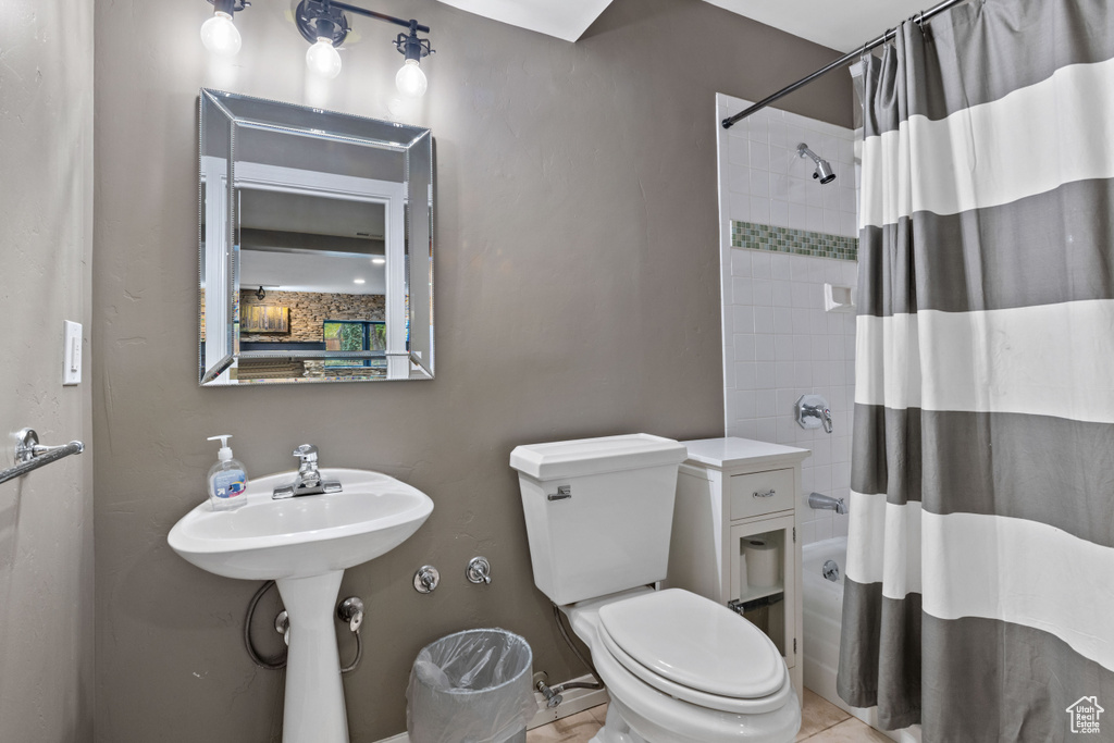 Bathroom featuring shower / bathtub combination with curtain, tile flooring, and toilet