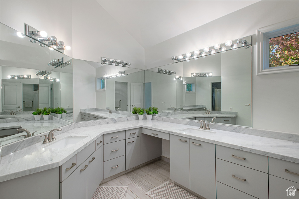 Bathroom featuring lofted ceiling, tile floors, and dual bowl vanity
