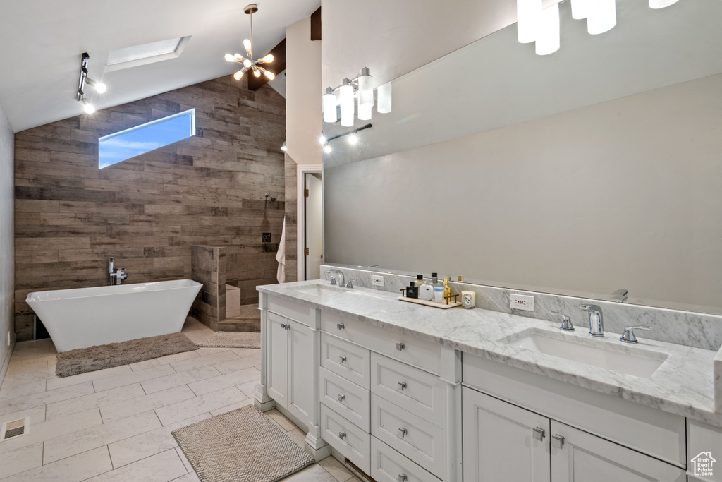 Bathroom featuring a notable chandelier, double vanity, tile walls, tile floors, and a bath