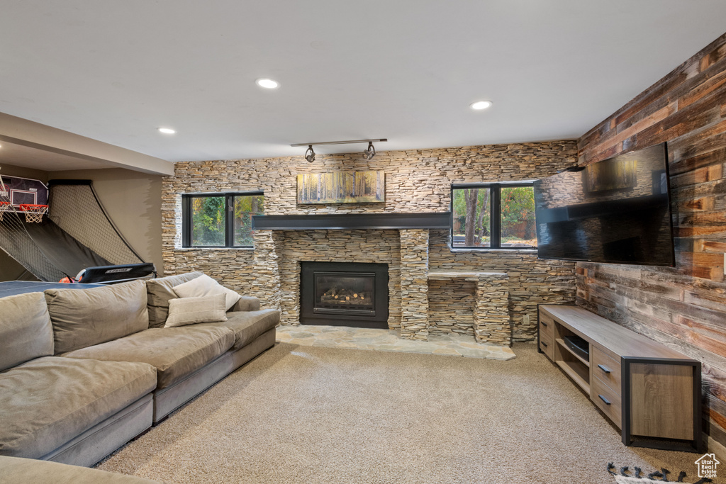 Living room with rail lighting, plenty of natural light, light carpet, and a stone fireplace