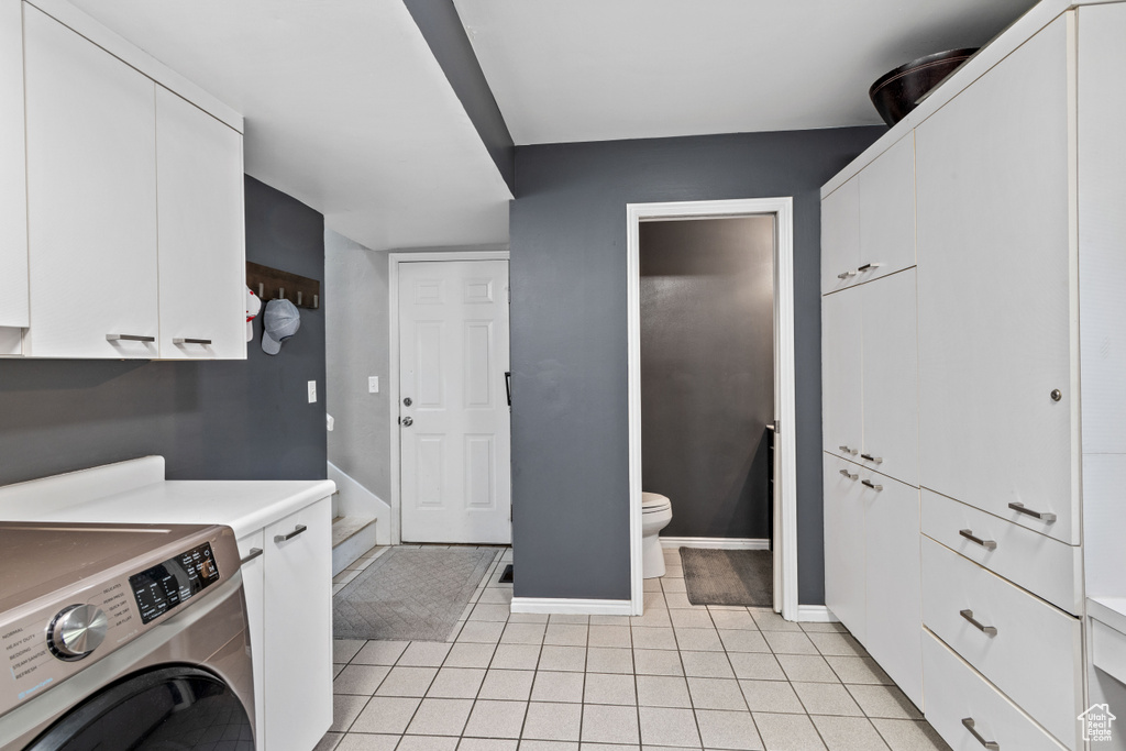 Laundry room featuring cabinets, light tile floors, and washer / clothes dryer