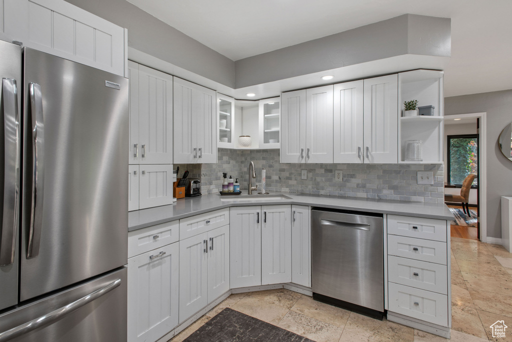 Kitchen with white cabinets, appliances with stainless steel finishes, light tile floors, and sink