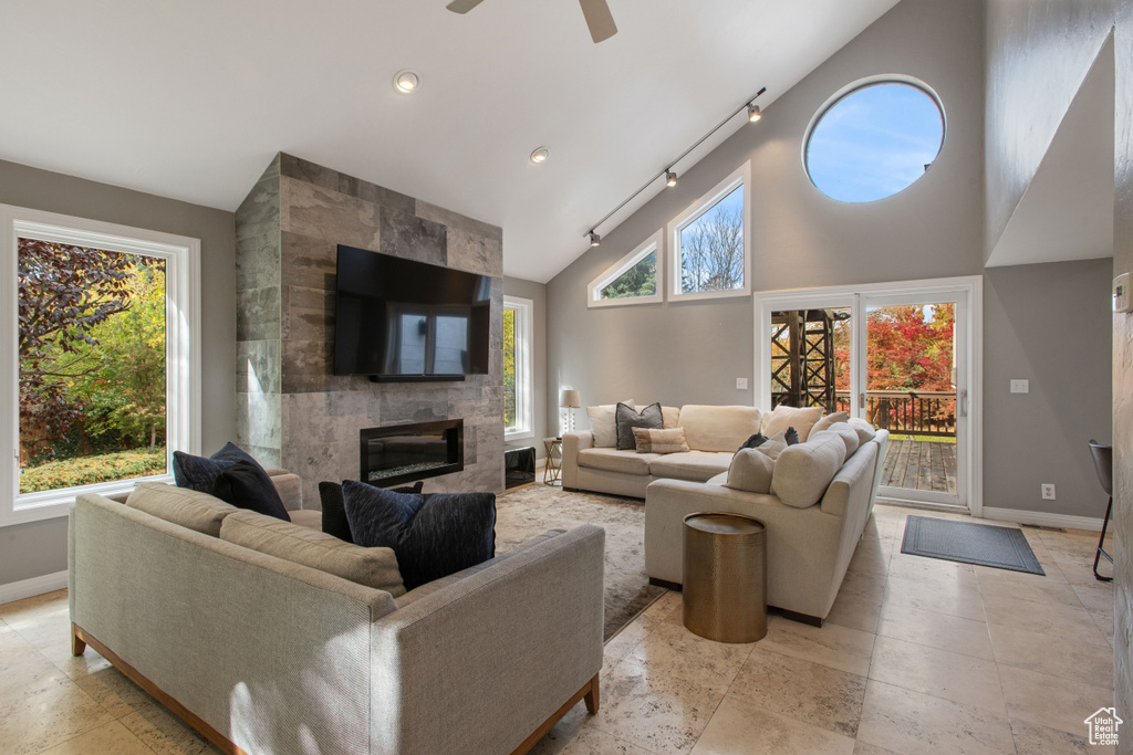 Tiled living room with rail lighting, a wealth of natural light, a fireplace, and ceiling fan