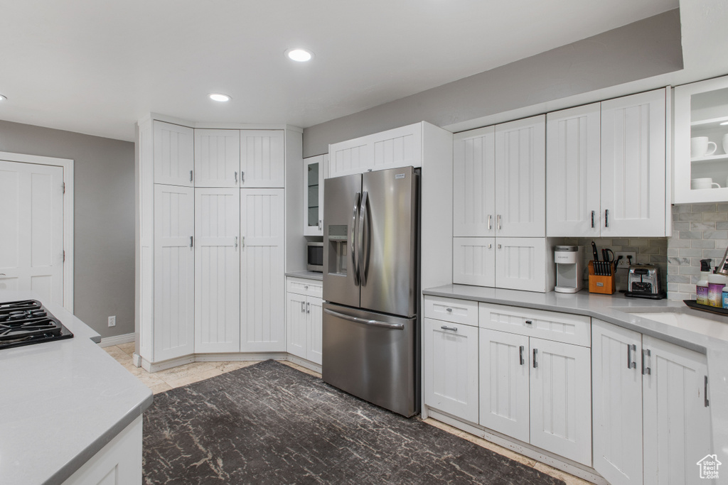 Kitchen with white cabinets, backsplash, and stainless steel refrigerator with ice dispenser