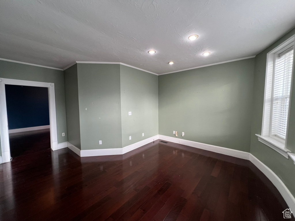 Spare room featuring dark wood-type flooring and ornamental molding