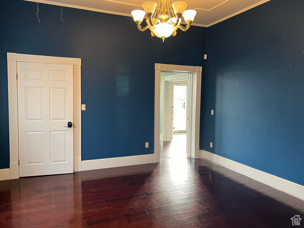 Unfurnished room with dark hardwood / wood-style flooring, a notable chandelier, and crown molding