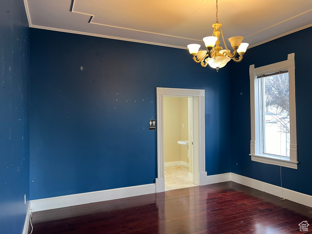 Unfurnished room featuring hardwood / wood-style floors, a chandelier, and ornamental molding