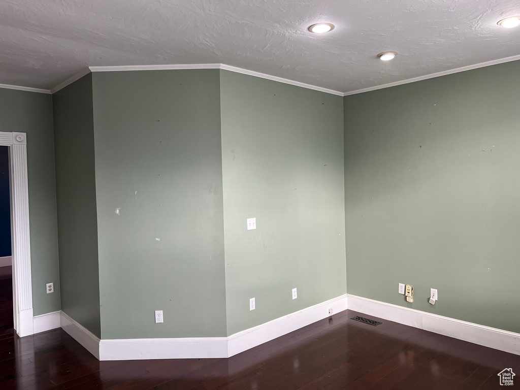 Unfurnished room with dark wood-type flooring, crown molding, and a textured ceiling