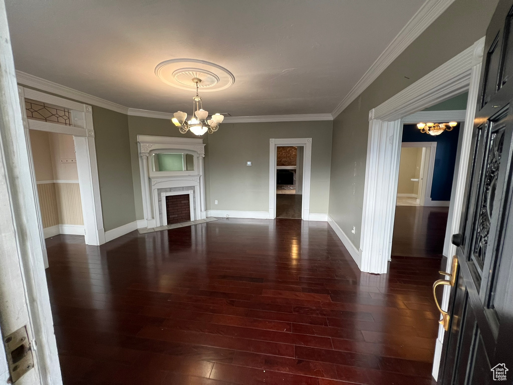 Spare room featuring a chandelier, dark hardwood / wood-style floors, and crown molding