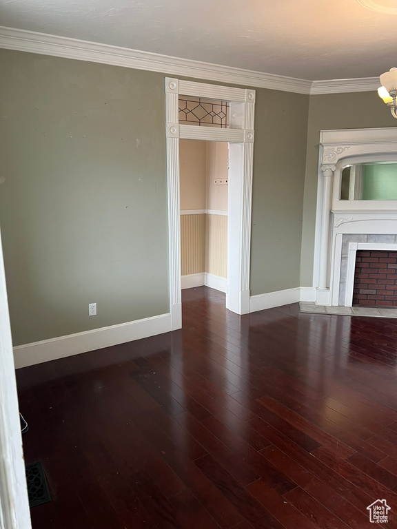 Unfurnished living room featuring dark hardwood / wood-style floors and crown molding