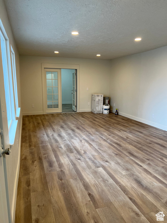 Unfurnished room with hardwood / wood-style floors, plenty of natural light, and a textured ceiling