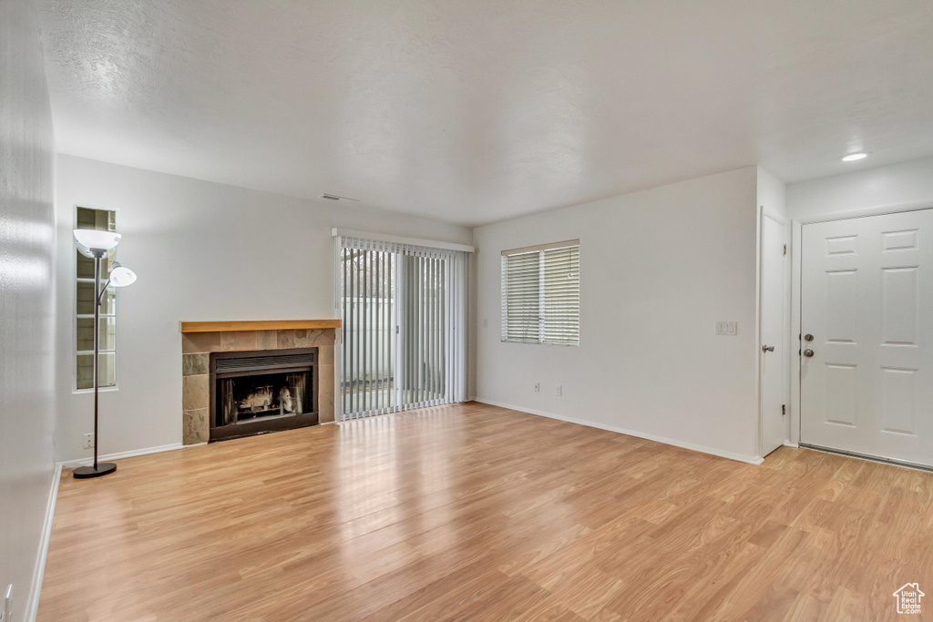 Unfurnished living room with light hardwood / wood-style floors and a tiled fireplace
