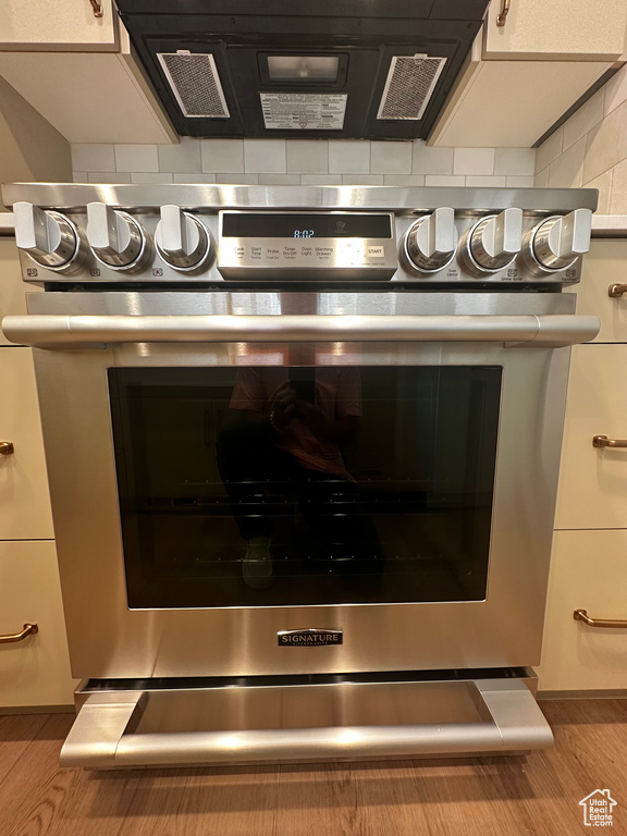 Interior details featuring appliances with stainless steel finishes, wood-type flooring, and decorative backsplash