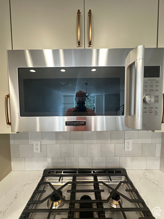 Interior details with light stone counters, stovetop, and tasteful backsplash