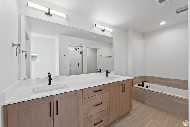 Bathroom with tile floors, dual bowl vanity, and separate shower and tub