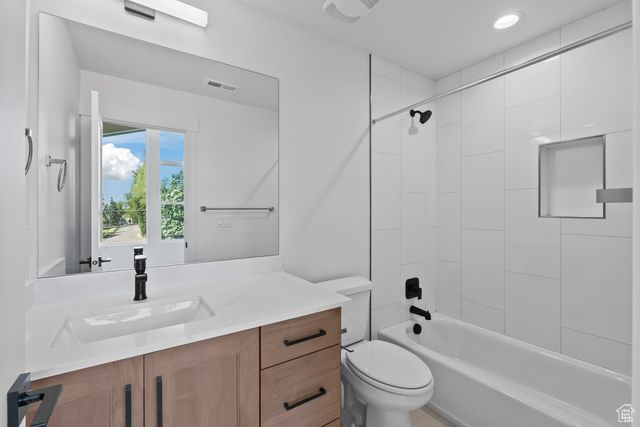 Full bathroom with vanity, toilet, and tiled shower / bath combo