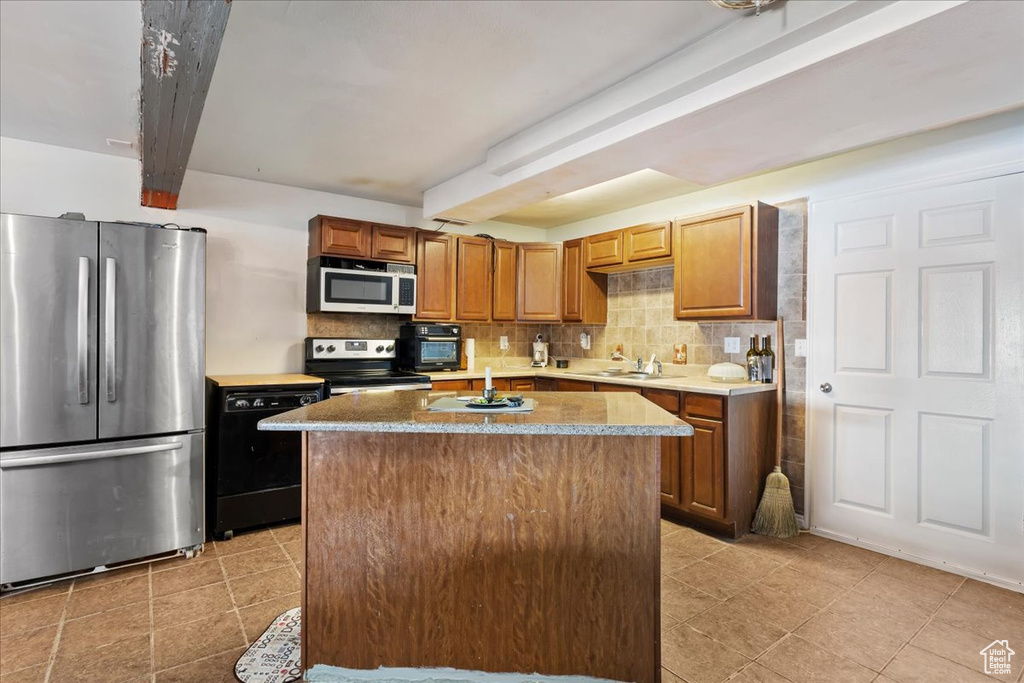 Kitchen featuring a center island, light tile floors, stainless steel appliances, and backsplash